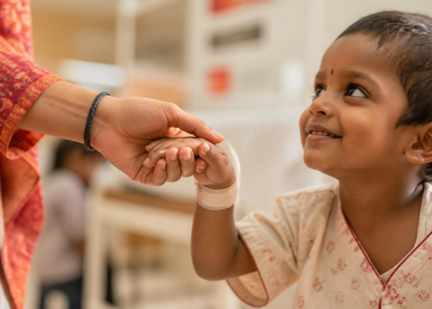 A caregiver gently holds a child's hand